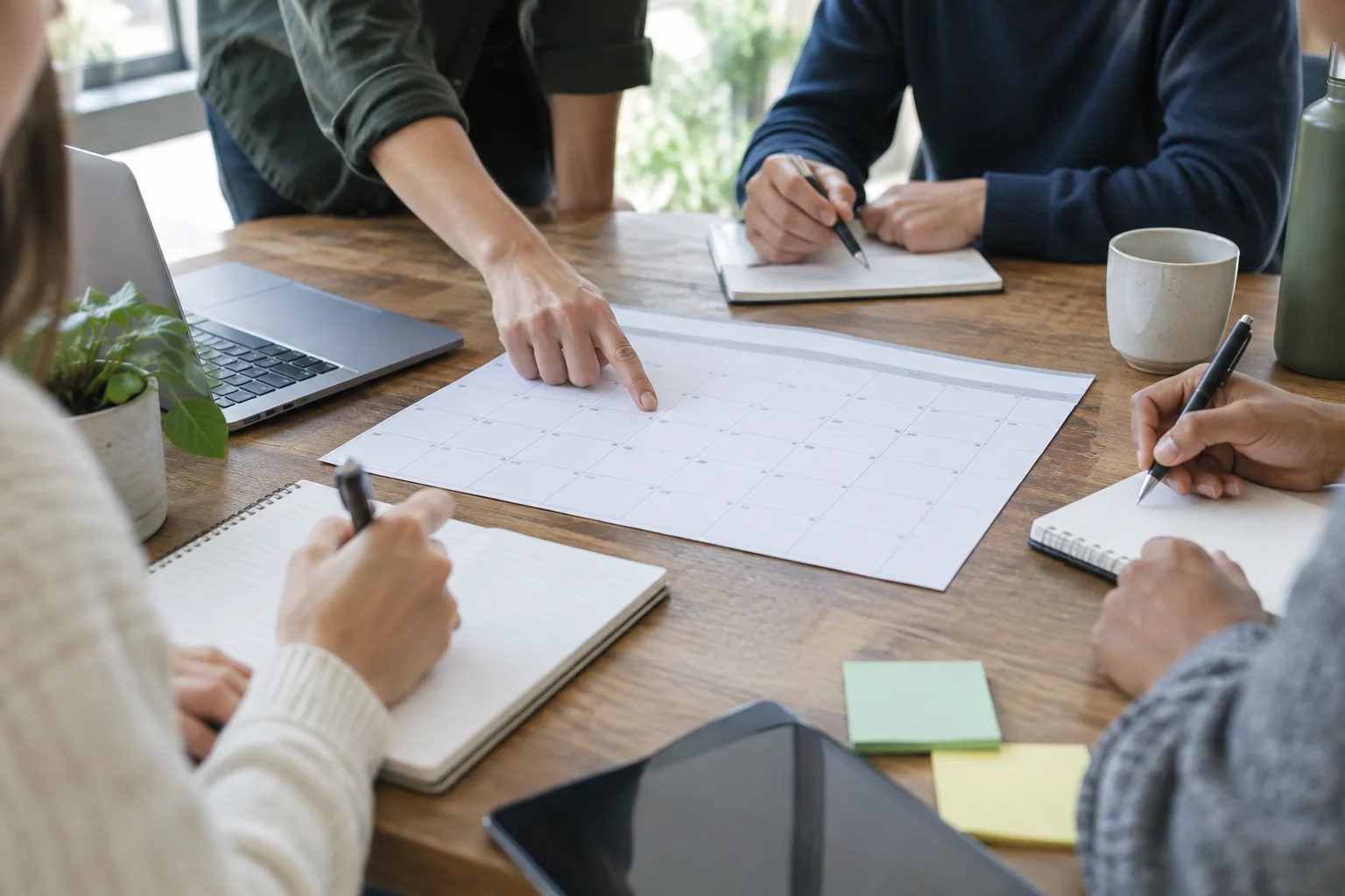 Des mains prennent des notes et organisent un essai de nouvelle règle de travail autour d’un calendrier vierge.