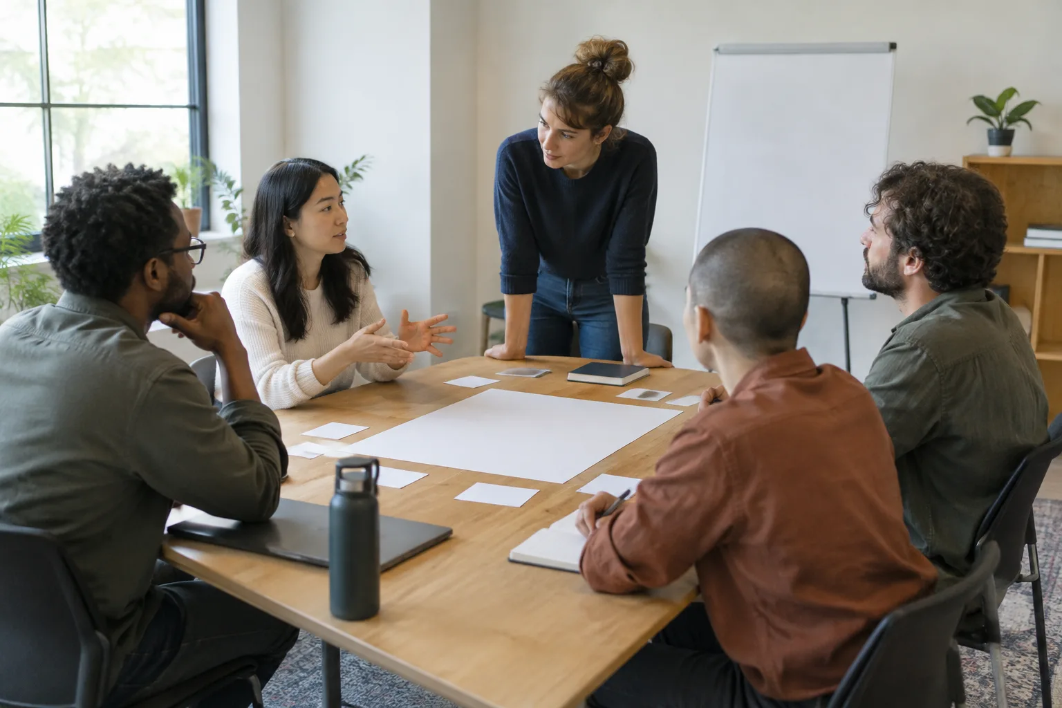 Des collègues échangent autour d’une table en observant des notes de travail.